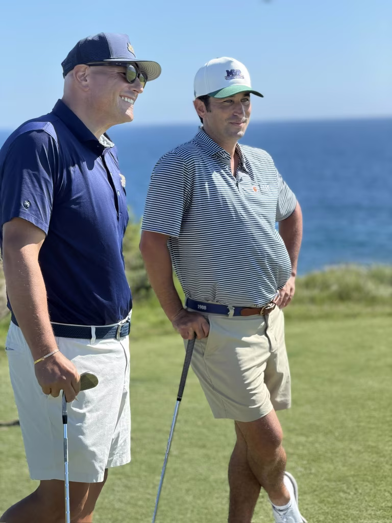 MVP Accident Attorneys founder Brett Sachs and Jake Adams laughing together on an oceanside tee box.